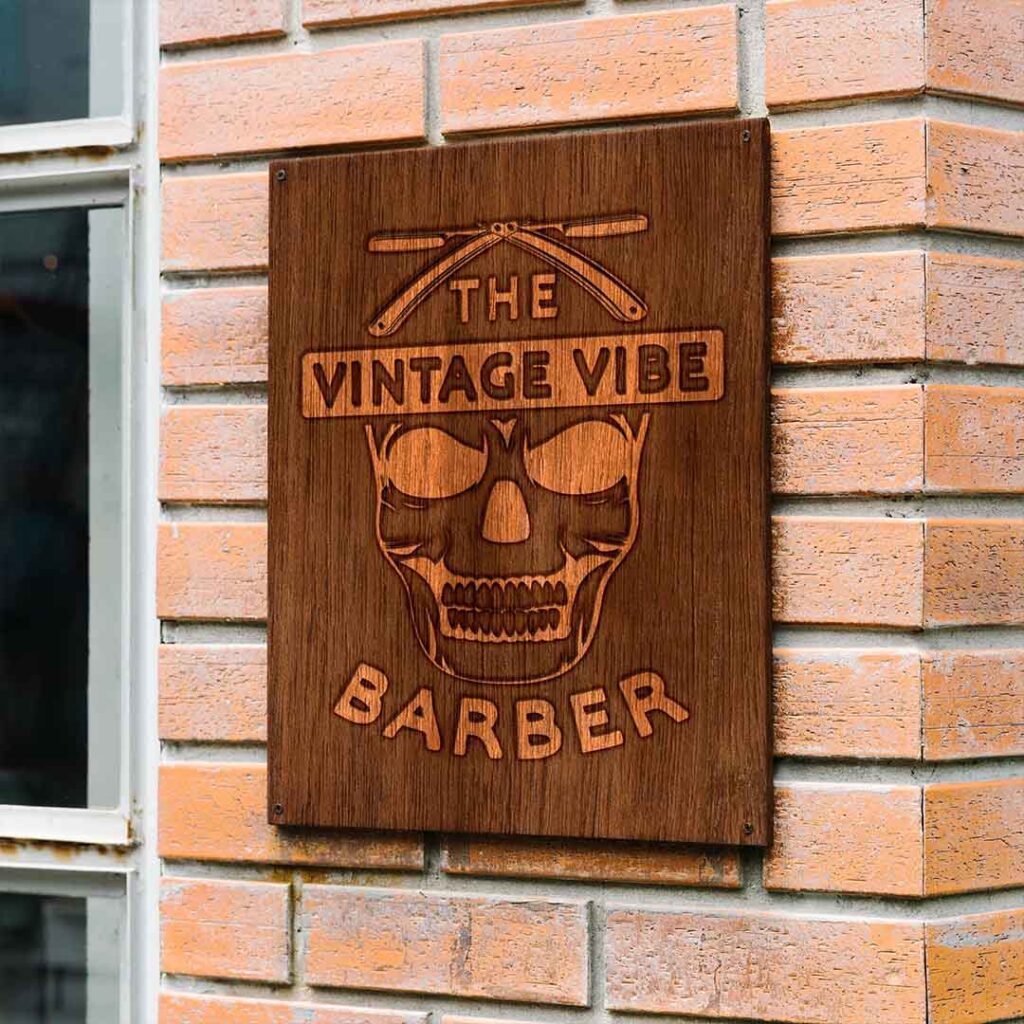 The Vintage Vibe Barber Logo design, made up of a skull with two hair cutting blades above it, mocked up on a wooden plaque.