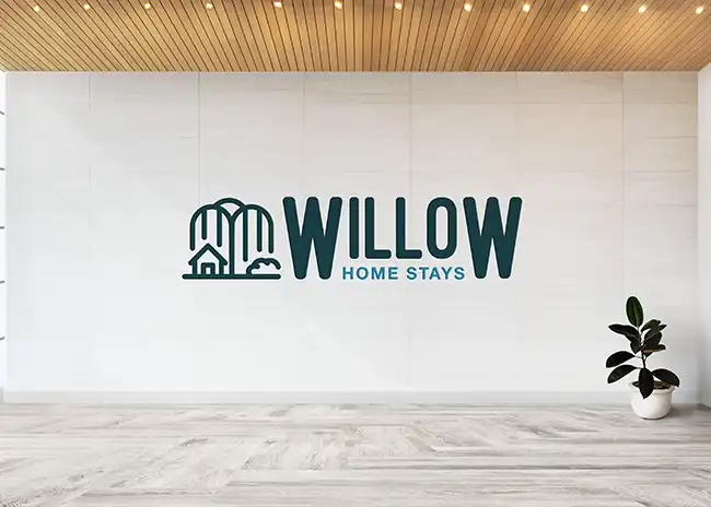 Minimalist logo for Willow Home Stays, featuring an outline of a house and willow trees alongside bold text, displayed on a modern, well-lit interior wall with wooden ceiling and potted plant.