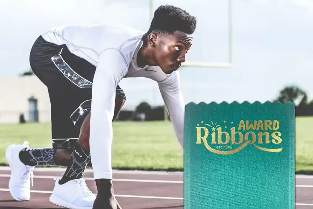 Focused male athlete in a starting position on a track field, with a ribbon printing company logo embossed onto a ribbon