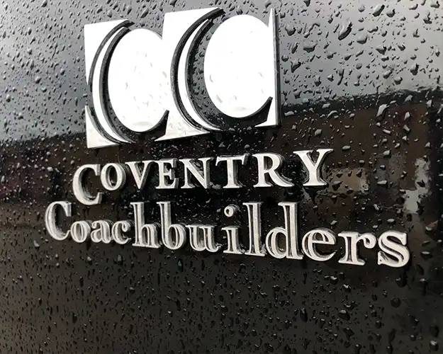 Detailed close-up of a vehicle's side featuring a 3D metallic logo for Coventry based business with water droplets, reflecting craftsmanship and quality