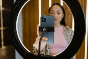 Smartphone mounted in a ring light with a blurred creator adjusting the phone for a tiktok shoot