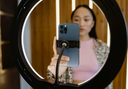 Smartphone mounted in a ring light with a blurred creator adjusting the phone for a tiktok shoot