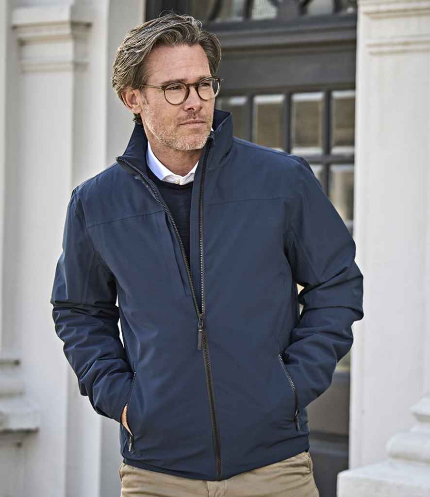 Man wearing a plain navy softshell jacket, ideal for custom embroidery or branded outerwear—smart and weather-resistant option for teams or staff.