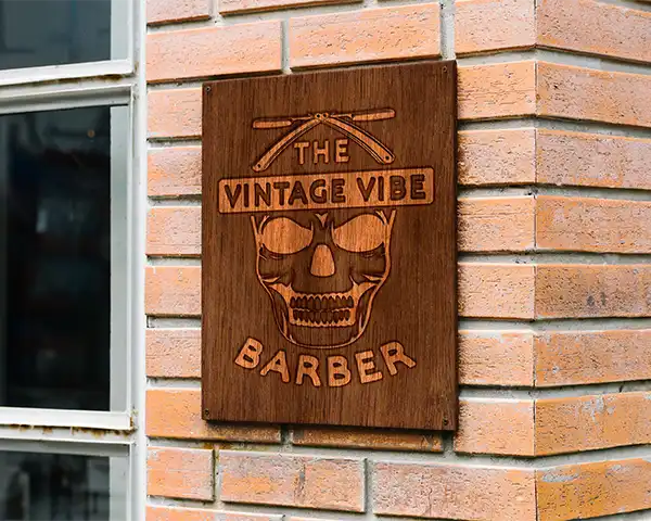 The west midlands based Vintage Vibe Barber wooden sign with engraved skull and scissors logo mounted on brick wall – rustic barbershop branding design