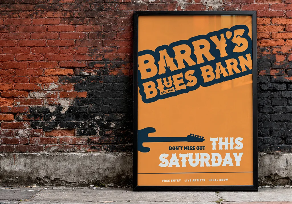 Framed orange Blues Barn event poster leaning against a weathered brick wall.