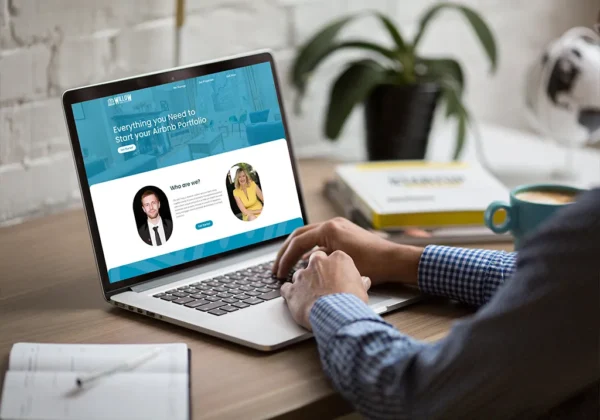 Person using a laptop showing the Airbnb coach website on a desk with coffee and notebooks.